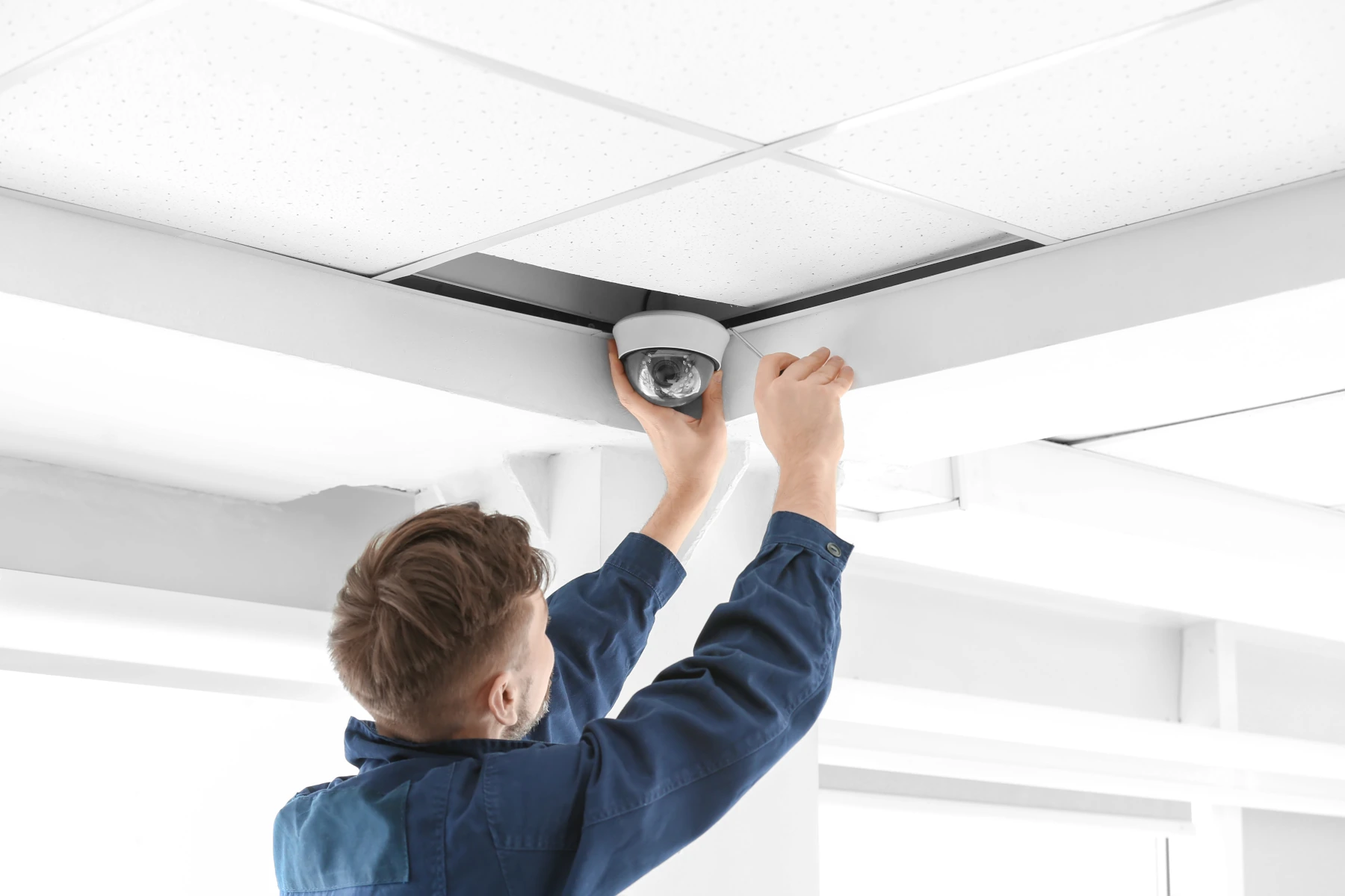 A small business owner mounting a security camera above a shop entrance
